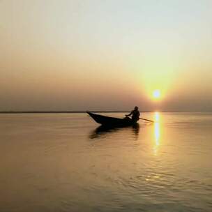 夕阳背景下划船的渔夫