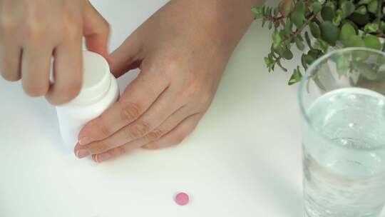 女性手打开罐子，在一杯水丸和药物的背景下