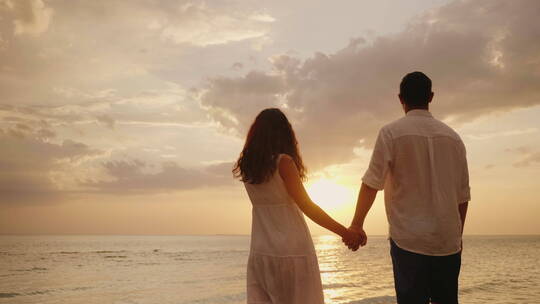 情侣站在水里看着海上的日落