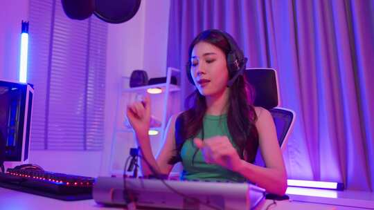 亚洲年轻的音频DJ女人在麦克风上唱一首歌来广播。