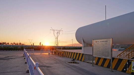 夕阳下高压电线塔附近巨大的储气罐航拍视频素材模板下载