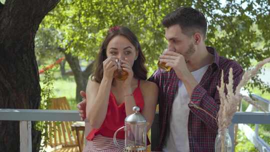 年轻快乐的夫妇坐在户外的小桌旁聊天喝茶
