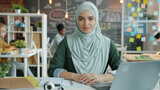 戴头巾的美丽穆斯林妇女坐在办公桌前工作的慢动作肖像高清在线视频素材下载