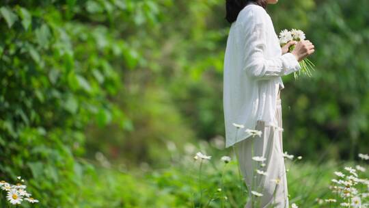 女青年拿着一束鲜花在春天草地散步慢镜头