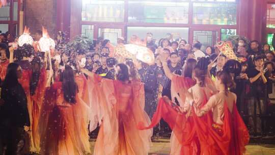 人群中女子持鱼形灯笼表演