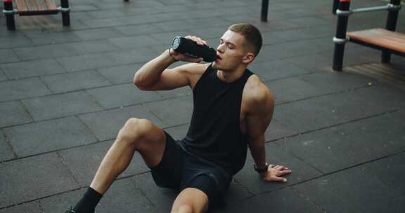 运动员在锻炼时休息，在户外用瓶子喝水