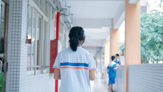 中学女生在学校教学楼走廊上行走的背影
