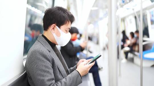 年轻人戴着口罩在地铁站使用手机