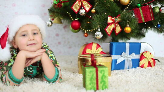 小女孩开心的趴在圣诞树旁边视频素材模板下载