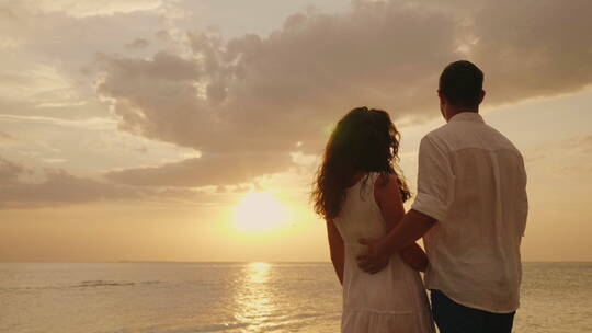 恋爱中的年轻夫妇拥抱在一起看日落