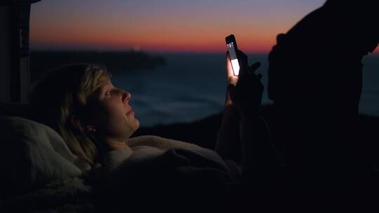 女人在海边露营时玩手机