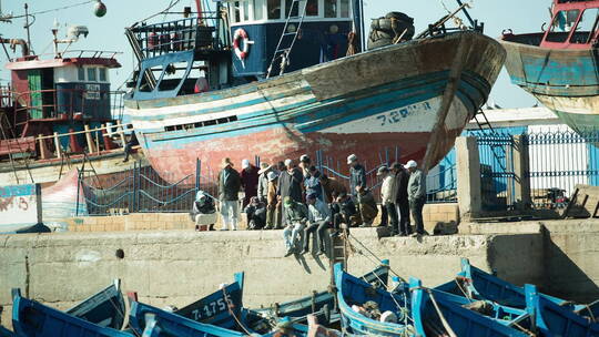 索维拉船和坐在码头上的渔民