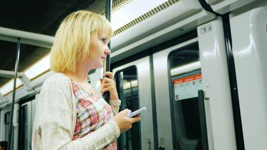 在地铁车厢玩手机的女人