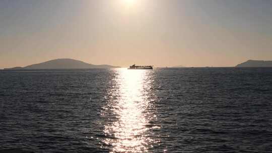 阳光明媚的傍晚，在马尔马拉海上航行的渡船剪影。阳光反射和遥远的岛屿