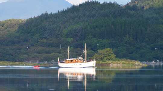 木船与小十二宫船航行在苏格兰的一个湖与森林和山脉在backgr
