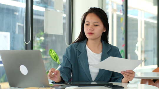 一个女人坐在桌子旁，桌上放着笔记本电脑和