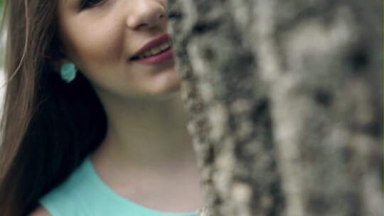 好女孩在树后微笑视频素材模板下载