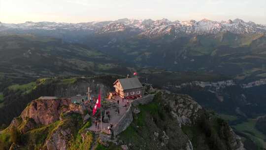 清晨无人驾驶飞机可以看到瑞士山顶，山上有餐厅和第一批客人。瑞士国旗视频素材模板下载