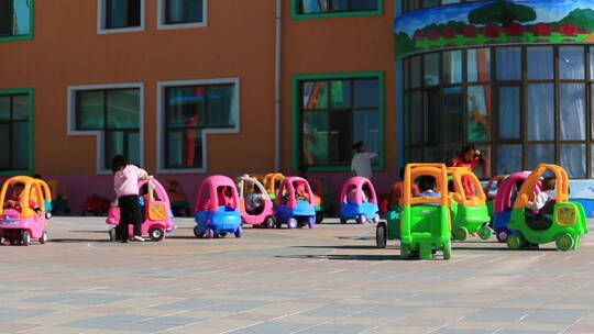 幼儿园空地上开玩具小车玩耍的孩子们视频素材模板下载