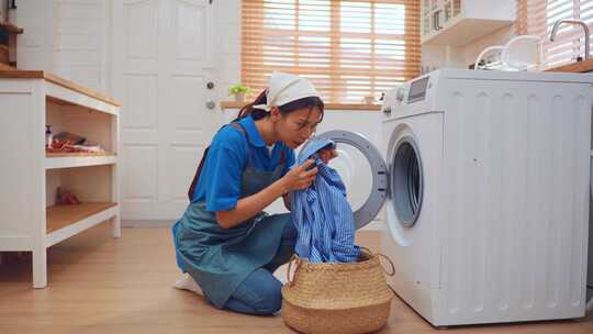 亚洲年轻女清洁工把脏衣服放在家里的洗衣机