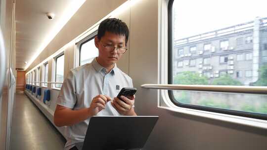 男子出差途中火车上使用笔记本电脑手机办公