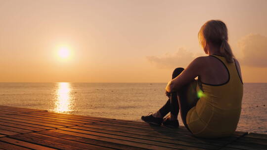 一个女人坐在码头看日出