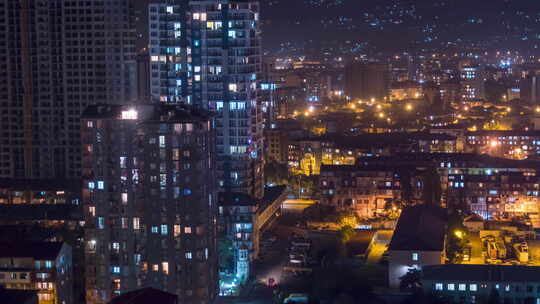 城市中夜间窗户照明变化的多层建筑。延时视频素材模板下载