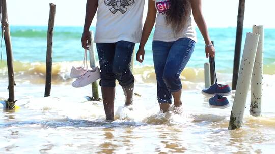 夫妇赤脚向海岸走去慢镜头