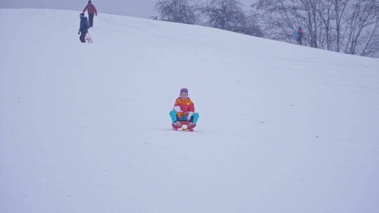 女孩骑着雪橇滑下山