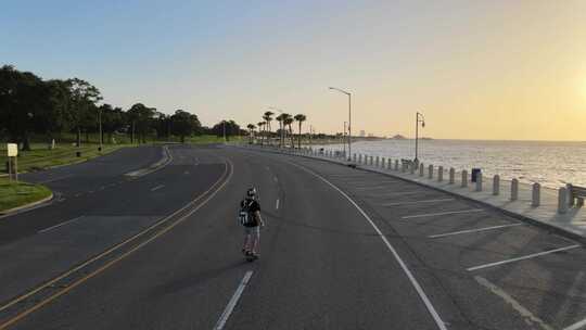 美国新奥尔良湖滨大道空荡荡的高速公路上，一名男子骑着电动滑板。trac