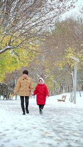 走在公园雪地里的中国母女形象