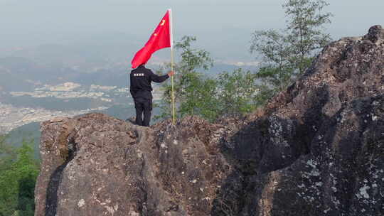 山顶人员手持国旗眺望远方