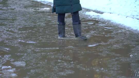 穿厚外套的人在雪后积水里行走