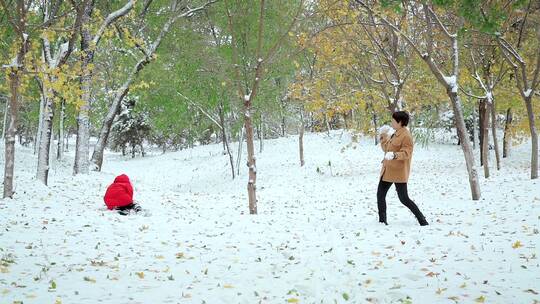 在公园里打雪仗的一对中国母女