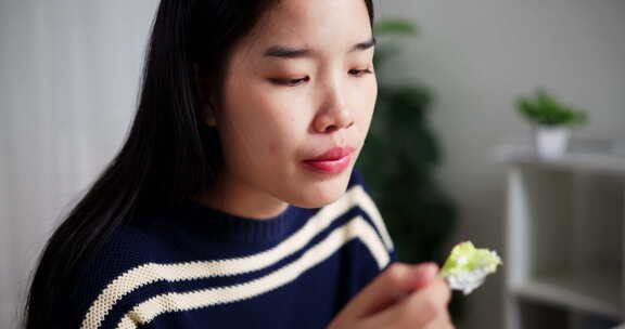 年轻的亚洲女人喜欢在家里的餐桌上吃早餐。