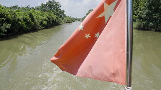 在湿地河流上航行的船红旗飘扬