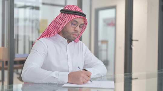 年轻的阿拉伯人在工作中写商业报告