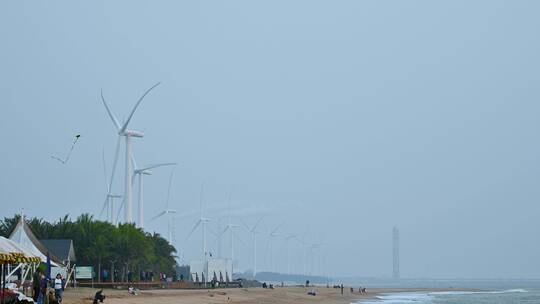东方市鱼鳞洲沙滩上的游客与风力发电机。视频素材模板下载