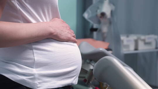 医学会诊中孕妇手触摸腹部的侧视图