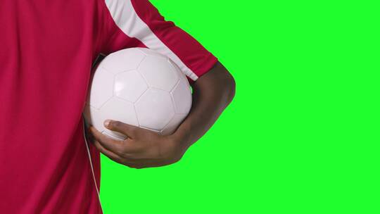 绿幕背景前足球运动员抱着足球的特写镜头