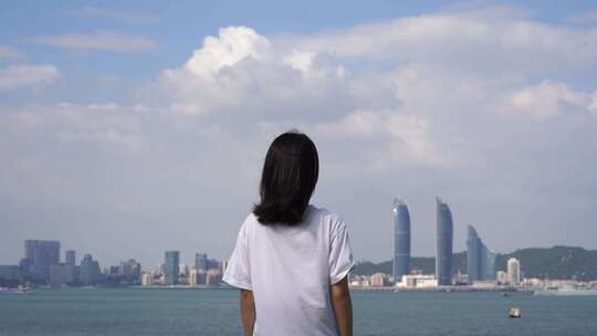 女孩站在城市海边吹风看风景看海青春少女