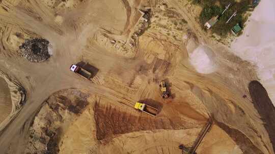 黄色挖掘机将沙子装入自卸车。