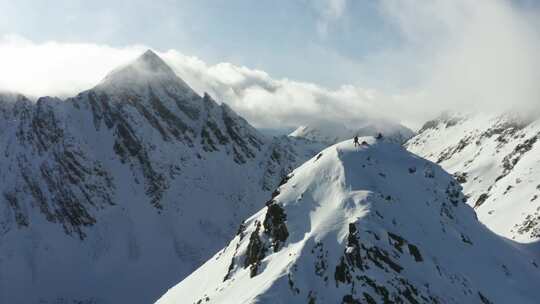 站在雪山顶上的人，手里拿着滑雪板