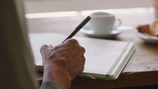 女人在咖啡馆里手写笔记本