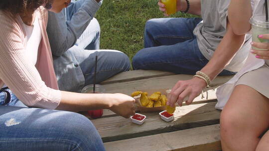 坐在公园的长椅上吃鸡块的朋友视频素材模板下载