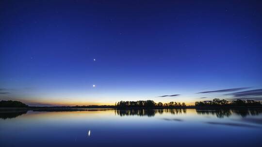 夜晚湖面倒影下美丽的蓝色布满行星的天空