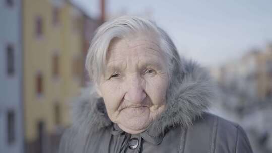 穿着毛皮大衣的老妇人在天空下微笑，脸上有视频素材模板下载