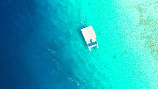空中，小型旅游船在珊瑚礁上空的热带水晶般清澈的绿松石海水中航行
