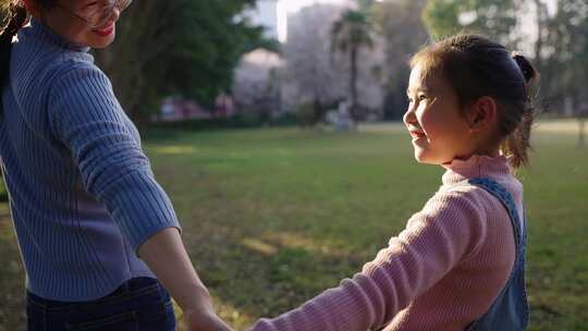 小女孩和妈妈牵手走在公园散步亲子陪伴