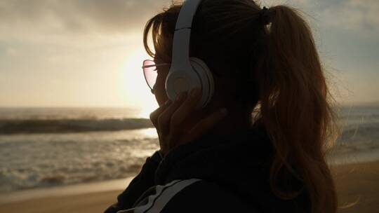 女孩在沙滩上听音乐